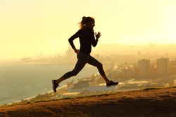 Full body profile of runner woman running at sunset in city outskirts