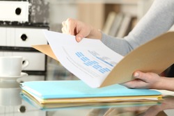 Close up of woman hands checking documents on folders sitting on a desk at home
