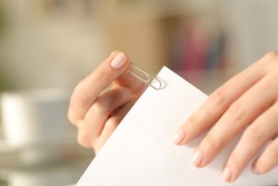 Close up of a woman hands putting a paper clip on a sheet at home