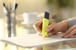 Close up of a woman hand underlining text on document with marker on a desk at home