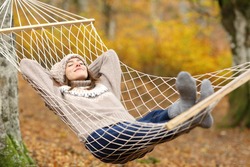 Full body portrait of a relaxed woman resting on hammock in autumn holiday