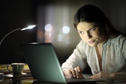 Suspicious entrepreneur woman checking laptop content late hours in the night at home