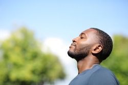 Profile of a man with black skin breathing fresh air in nature a sunny day