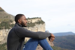 Profile of a serious man with black skin contemplating sitting in the mountain