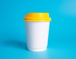 Front top view, white coffee paper cup yellow lid, filled with hot black coffee(americano), no sugar milk, ready to drink, refreshing. aroma awake fresh to work placed on  Blue isolated background