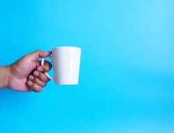Man hand holding a white coffee cup, filled with hot black coffee(americano), no sugar no milk, ready to drink, refreshing. aroma awake fresh to work placed on a blue isolated background