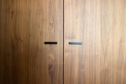 Beautiful brown wooden oak doors of a cabinet with black modern handles modern background texture close-up