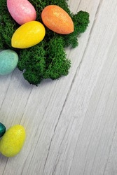 Happy Easter holliday concept, colorful easter eggs with green moss on white wooden background texture top view, copy space, bright colors space for text
