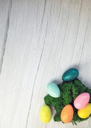 Happy Easter holliday concept, colorful easter eggs with green moss on white wooden background texture top view, copy space, bright colors space for text