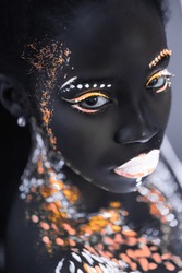 portrait of young african woman with colorful abstract make-up on face. unusual, interesting, fantastic shoot. body art, neon lights, fluorescence. black and white