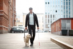 blind caucasian man guided by puppy. pet icon sign or symbol. guy with companion friend in city streets
