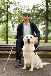 25 years old man suffer from blindness, get help by dog guide, sit having rest outdoors
