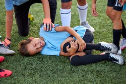 little caucasian boy fell to his knee, ache in joints during football game outdoors, injury during sport competition