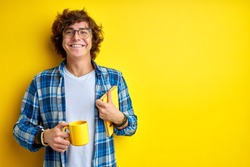 happy student guy is ready to study, stand with cup of tea and book in the morning, begin day with hot tea, smiling