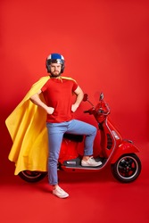 strong super hero man in cloak stand next to motorcycle, ready to conquer the world, isolated on red background