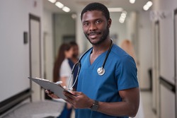 Handsome African American Doctor In Blue medical Unifrom with clipboard in hospital