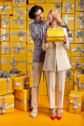 Pleasant Guy Give New Yellow Hand Bag To Girlfriend, Congratulating, Please Woman Closing Eyes Makeing Surprise, Celebrating Birthday Or Anniversary