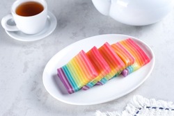 Kue Pepe or Kue Lapis Pelangi or Rainbow Sticky Layer Cake is Indonesian traditional dessert made from rice flour and coconut milk, steamed layer by layer served on white plate. Selective focus.