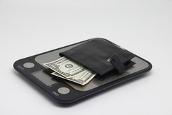 Wallet with banknotes on electronic kitchen scales. Icheta symbol and family finance planning