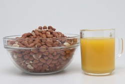 Peanuts in a bowl and a glass of orange juice. Separate on a white background