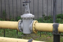 Shut-off valve on gas pipe. Fragment of pipeline with valve. Valve on pipe in boiler room. Concept - shutting off gas supply. Flap to shut off gas flow. Yellow steel pipeline close up.