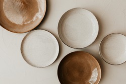 Five different size plate on beige background. Flat lay, top view. Brown and natural color plates. Textured grainy pattern on the plates.
