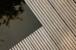 A wooden deck detail over a pond. Abstract architectural pattern detail of a timber decking in the park. Modern minimal concept, copy space. Parallel lines. 