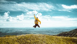 Hiker with backpack raising hands jumping on the top of a mountain - Successful man with arms up enjoying victory - Sport and success concept