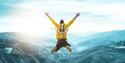 Man traveler on mountain summit enjoying nature view with hands raised over clouds - Sport, travel business and success, leadership and achievement concept