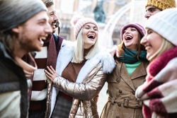 Young people wearing winter clothes having fun on city street - Group of happy friends socializing talking and laughing together - Youth lifestyle concept with guys and girls enjoying vacation days 