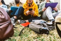 International students sitting together on green campus lawn - Group of high school teens studying outside college - Multiethnic millenial friends doing homework in university park - Academic concept