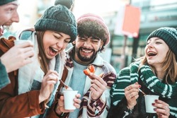 Happy friends having fun drinking mulled wine and hot chocolate at Christmas Market - Cheerful young people enjoying winter holidays on weekend vacation - Tourism lifestyle and friendship concept