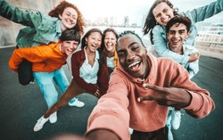 Multicultural group of friends taking selfie picture with smart mobile phone outside - Millenial people walking on city street - Life style concept with guys and girls hanging out together