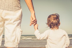 Father's hand lead his child son in summer beach nature outdoor, trust family concept