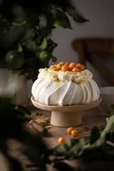 Pavlova meringue dessert on a table and greenery background