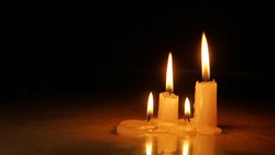 Burning candles on wooden table with black background, symbol of light and hope, copy space