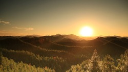 Beautiful sunset above mountains; the forest at orange sunset