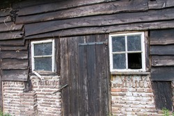 View of weathered doors, windows and barn boards of dilapidated and abandoned barn on a farm in countryside in the Netherlands