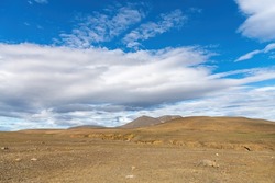 Panoramic view of the barren Icelandic Highlands with volcanos and mountains in the northern part of Iceland with a beautiful blue sky with large white fluffy clouds