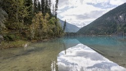 Pristine, calm and turquoise alpine lake reflecting its surroundings, Mount Robson PP, Canada