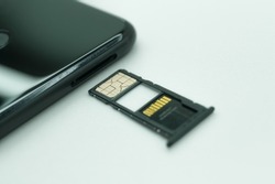 Installing a SIM card in a mobile phone. Open tray for SIM cards and micro memory cards. Selective focus, white background