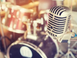 Microphone in a recording studio or concert hall with drum in out of focus background. : Vintage style and filtered process.
