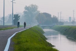 Elderly people in countryside bike road near little brook and bridge in fog location