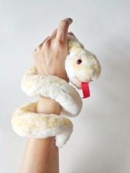 Cute White and yellow Snake doll wrapped around a woman's arm on white background. Playing with soft toy.