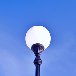 white street lamp on cast iron leg against blue sky on a sunny day