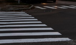White stripes of pedestrian crossing. Focus at the center of image