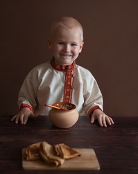 Russian folk style. a boy in a Russian folk shirt. tradition of Russia. Carnival costume. Russian festivities. porridge in a clay pot. Bogatyr. peasant. Maslenitsa. holiday. Maslenitsa collection