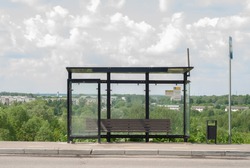 Empty public transport stop in summer. Self-isolation. Bus and minibus stops. Glass stop with a bench and a trash can. Stop without people, without passengers. bus stop sign