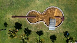 aerial view of a violin-shaped lake in the green garden with palm trees.
