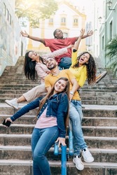 Group of happy young friends having fun sitting on the handrail of a stairs in the city center - Friendship concept - Focus on the bearded man


